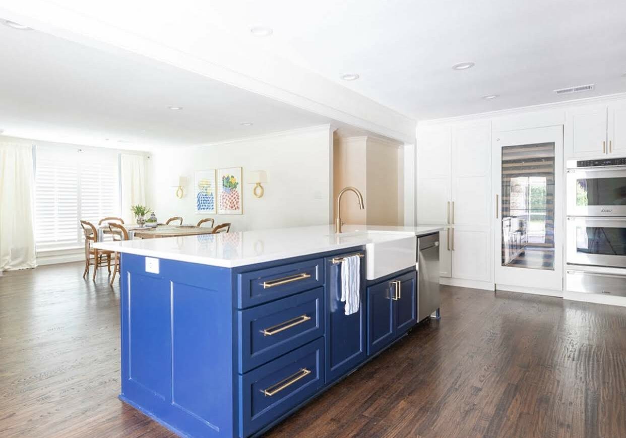Bold blue kitchen island in white kitchen with wood stained floor